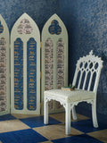A midnight blue wallpaper with cut-out silver dashed bramble design, pictured with room divider and white chair