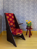 A contemporary design hatched from West African adire fabrics, this indigo blue wallpaper with a small pattern repeat utilises geometric shapes and stripes, pictured with a red armchair and yellow potted marigolds