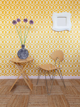 Yellow and off-white sun and moon surface printed wallpaper by contemporary artist Zoe Gibson with wooden desk and chair and purple flowers