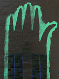 Close-up shot of a green embroidered wallhanging made from a cushion cover second depicting a broken hand sewed back together