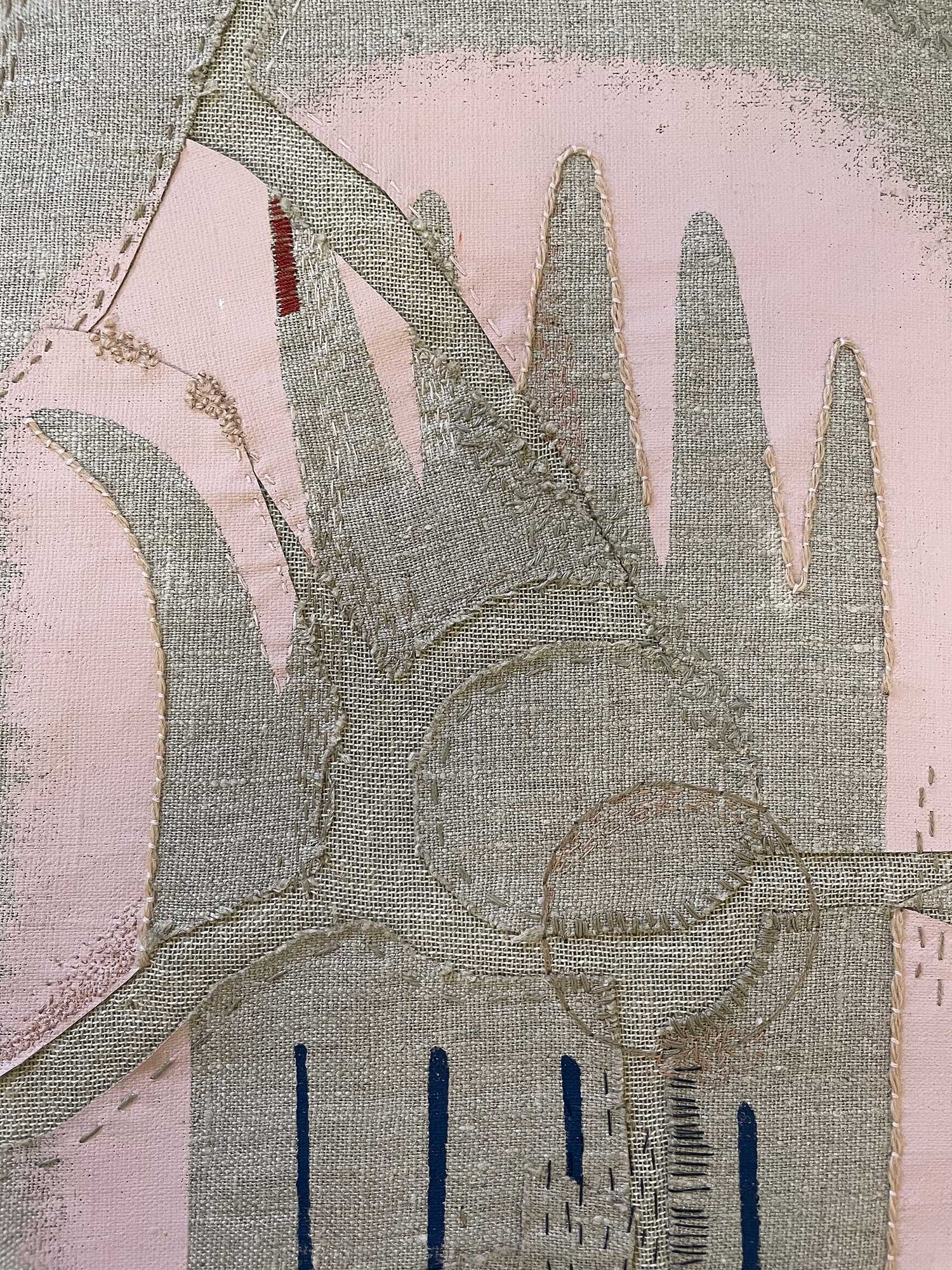 Close-up shot of a pink and grey embroidered wallhanging made from a cushion cover second depicting a broken hand sewed back together