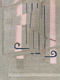 A pink and grey embroidered wallhanging made from a cushion cover second depicting a broken hand sewed back together