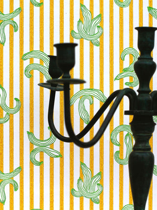 A quirky and eccentric wallpaper by artist Ferris featuring yellow stripes and green cucumber motifs, close-up with candle