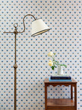 Magical realism pop-art wallpaper in Delphinium blue colourway, with anthropomorphic flowers like winking eyes, with rose flowers and lampshade