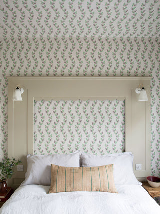 An archival design dating back to 1800, this wavy wallpaper displays falling oak leaves in green and brown, pictured wallpapered behind and above a bed